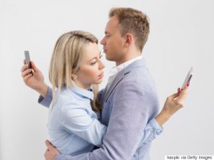 Couple embracing and still using their mobile phones